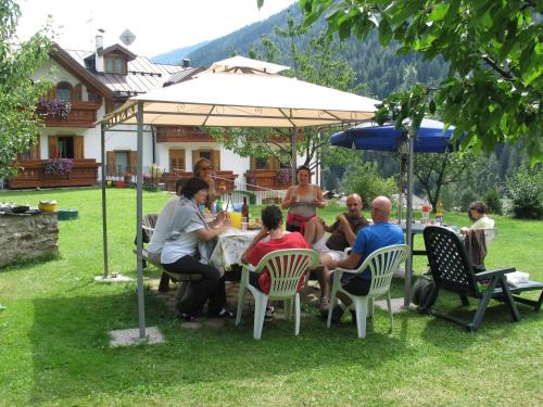 a group of people sitting at a table under an umbrella at Casa Bamby in Cogolo