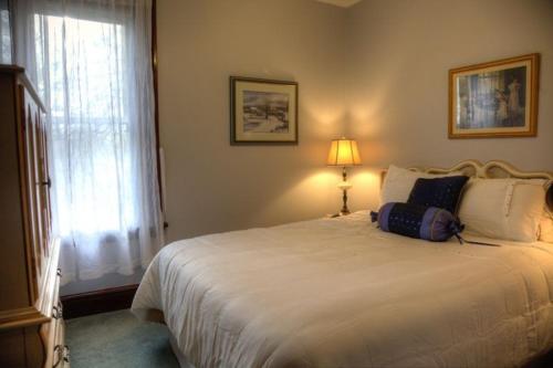 1 dormitorio con 1 cama blanca con lámpara y ventana en Pemberley House Bed and Breakfast, en Seaforth