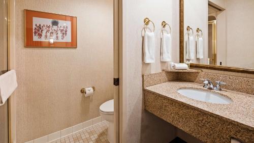 ein Badezimmer mit einem Waschbecken, einem WC und einem Spiegel in der Unterkunft Inn at Santa Fe, SureStay Collection by Best Western in Santa Fe