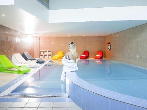 a woman standing in front of a swimming pool at Novotel Zurich City West in Zürich