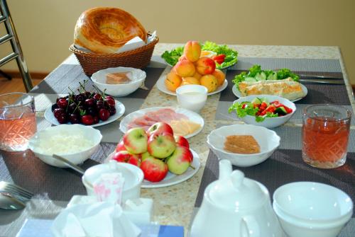 einen Tisch mit Teller mit Lebensmitteln und Schalen mit Früchten in der Unterkunft Chinor Garden Hotel - Free Airport Pick-up and Drop-Off in Taschkent