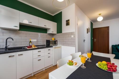 a kitchen with white cabinets and a table with fruit on it at Sleepway Apartments- Green Dream in Poznań