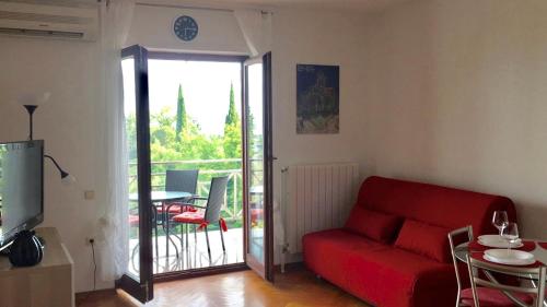 a living room with a red couch and a balcony at Apartment Lapov in Ičići