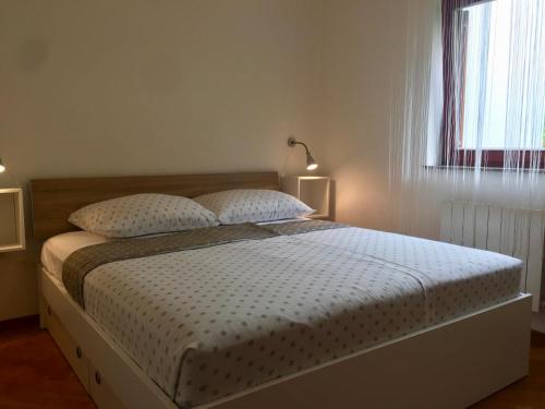 a bedroom with a bed with two pillows and a window at Apartment Lapov in Ičići