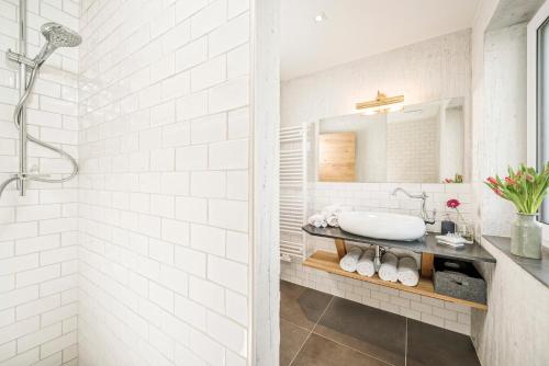 ein weißes Bad mit einem Waschbecken und einer Dusche in der Unterkunft Emma's kleines Hotel in Ramsau im Zillertal