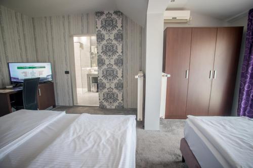 a bedroom with a bed and a desk and a computer at Garni Hotel Radović in Kragujevac