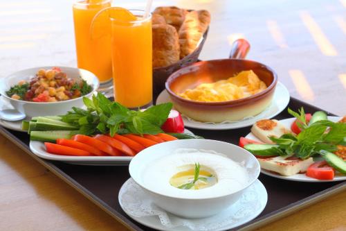 a tray with plates of food and bowls of soup and vegetables at La Siesta Hotel & Beach Resort in Khaldah