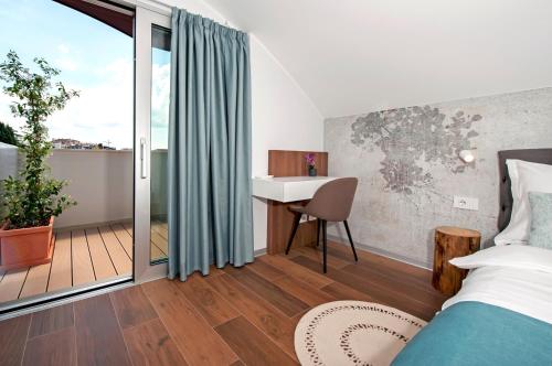 a bedroom with a bed and a desk and a balcony at The Q Superior - a penthouse with jacuzzi and sauna in Rovinj