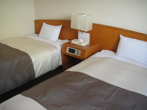 a hotel room with two beds and a lamp on a night stand at Hotel New Shizuoka in Shizuoka