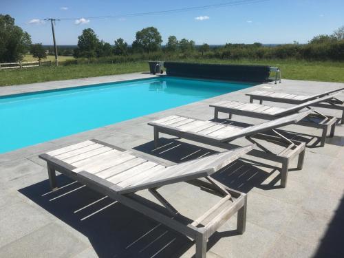 un groupe de chaises longues et une piscine dans l'établissement AU BORD DE LA FORET, à Couleuvre