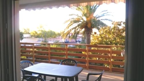 a table and chairs on a balcony with a palm tree at Résidence tout confort Cabestany in Cabestany