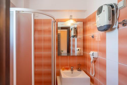 a bathroom with a shower and a sink and a mirror at Romantica Hotel in Agia Pelagia