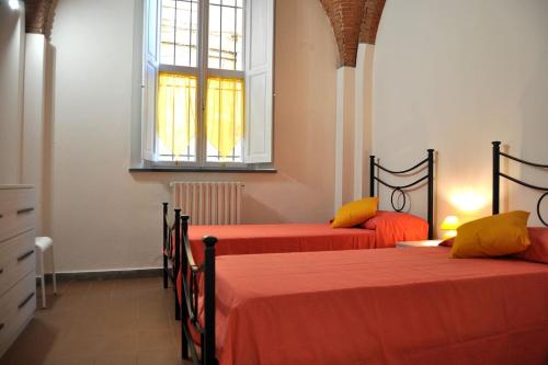 um quarto com 2 camas com lençóis laranja e uma janela em La casa di Dario, Dario's house. em Pisa
