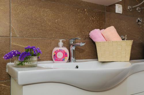 a bathroom sink with a bottle of soap and flowers at Apartment Petar in Kaštela