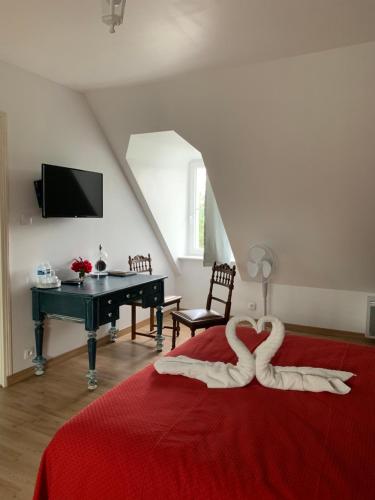 two swans sitting on a red bed in a bedroom at Moulin d'Amour in Chambon