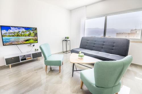a living room with a couch and chairs and a tv at The suite in Eilat
