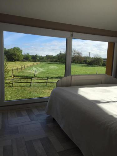 - une chambre avec une grande fenêtre donnant sur un champ dans l'établissement Villa contemporaine, à La Réorthe