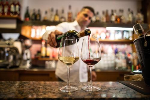 a man pouring wine into two wine glasses at Hotel Kennedy in Lido di Jesolo