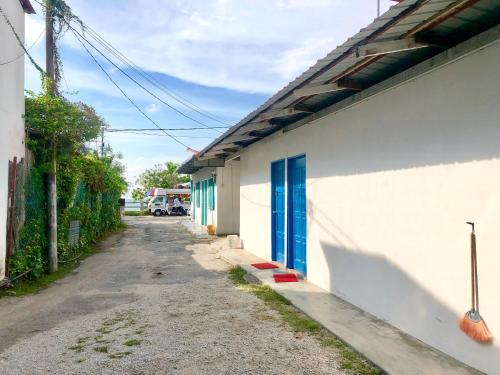 eine Gasse mit einer blauen Tür an der Seite eines Gebäudes in der Unterkunft Baba's Guest House By The Sea in Batu Feringgi