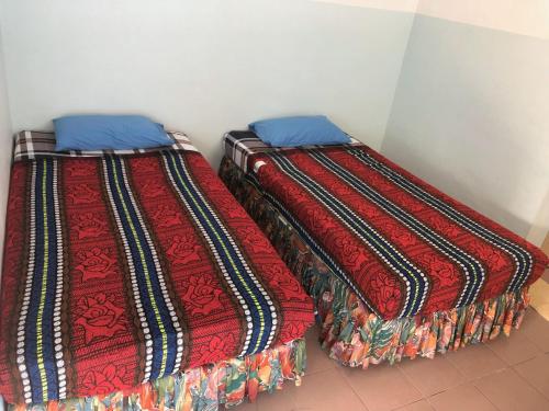 two beds sitting next to each other in a room at Baba's Guest House By The Sea in Batu Ferringhi