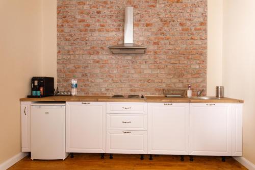 a kitchen with white cabinets and a brick wall at Stylish Flat in the Heart of Historical Center in Timişoara