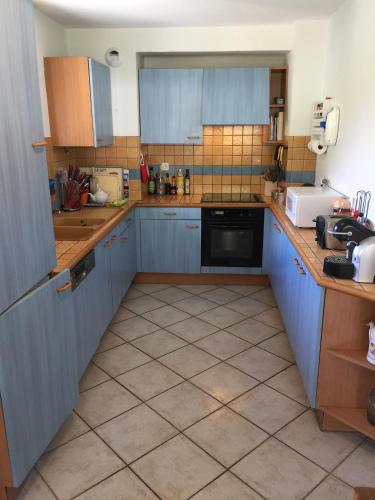 Il comprend une cuisine avec des placards bleus et du carrelage. dans l'établissement Appartement face au Mont Blanc & Glaciers, à Chamonix-Mont-Blanc