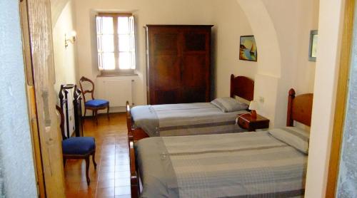 a room with two beds and a chair and a window at Convento del Carmine 4 in Fivizzano