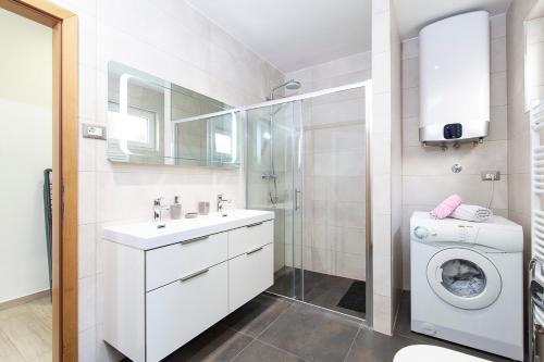a bathroom with a sink and a washing machine at Apartment Svemir in Primošten