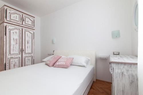 a bedroom with a bed with two pink pillows on it at Apartment Svemir in Primošten