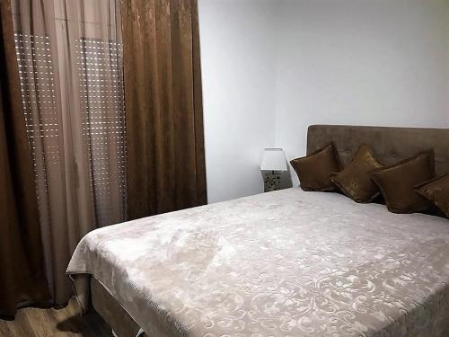 a bedroom with a large bed with brown curtains at Eko Apartmani Krackovic in Podgorica