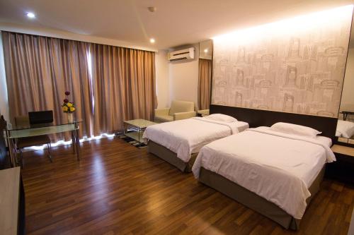 a hotel room with two beds and a desk at Golden City Rayong Hotel in Rayong