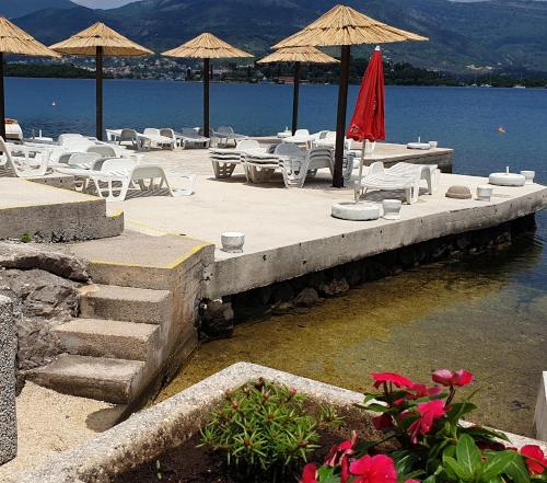 a dock with chairs and umbrellas on the water at Apartments Klakor PS in Tivat