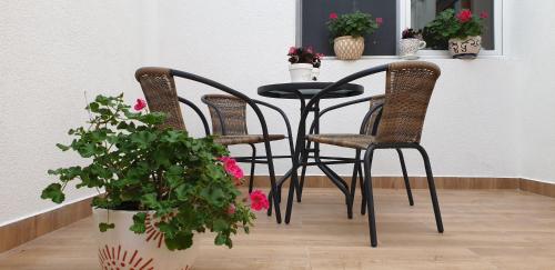 a black table with three chairs and a table with flowers at Lovely Private Flats FREE parking in Novi Sad