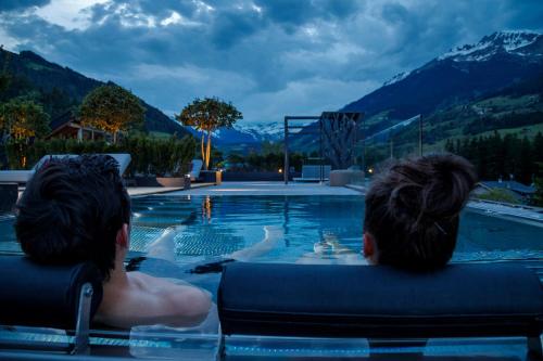 dos personas sentadas en una piscina en un complejo en Hotel Ratschingserhof, en Racines