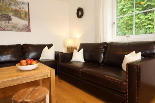 a living room with a leather couch and a bowl of fruit at Haus Chiemsee-Blick in Gstadt am Chiemsee