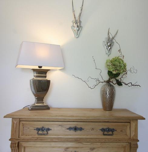 a lamp on top of a dresser with a vase of flowers at Haus Chiemsee-Blick in Gstadt am Chiemsee