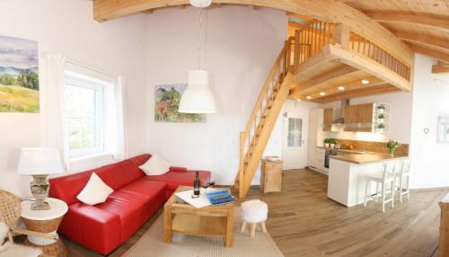 ein Wohnzimmer mit einem roten Sofa und einer Küche in der Unterkunft Haus Chiemsee-Blick in Gstadt am Chiemsee
