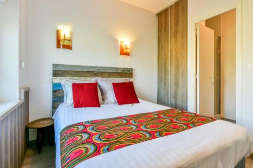 a bedroom with a large bed with red pillows at Logis Hostellerie du Neez in Gan