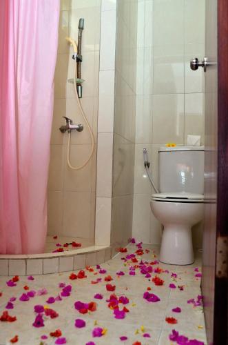 a bathroom with a toilet and flowers on the floor at Tanjung Sari Inn in Nusa Dua