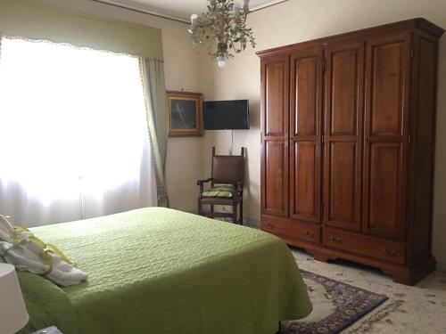 een slaapkamer met een groen bed en een houten kast bij Dimora Montpellier in Salerno