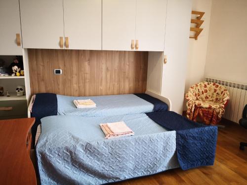 a bedroom with two beds with blue sheets and a chair at Maddy Appartamento in Porto Viro