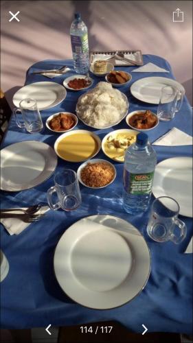 a blue table topped with white plates and bowls of food at The City Tourist Hotel in Anuradhapura