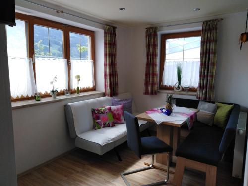 ein Wohnzimmer mit einem Tisch, Stühlen und Fenstern in der Unterkunft Landhaus Sarah in Dorfgastein