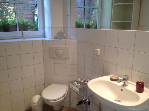 a white bathroom with a toilet and a sink at Pension Kunsthof Dahrenstedt in Dahrenstedt