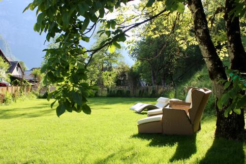two white chairs sitting in the grass under a tree at Chalet am Sonnenhang in Obertraun