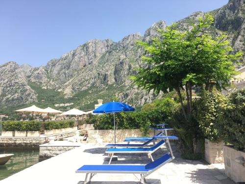 a group of blue lounge chairs and an umbrella at Ljuta Studios in Kotor