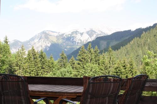 a wooden table and chairs on a balcony with mountains at Blockhütte Radmer in Radmer an der Hasel