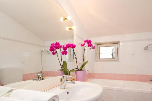 a bathroom with a sink and a tub and pink flowers at Villa Sveta Eufemija Bed end Breakfast II in Rovinj