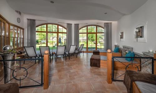 a living room with a table and chairs and windows at Hotel Hubertushof in Grossarl