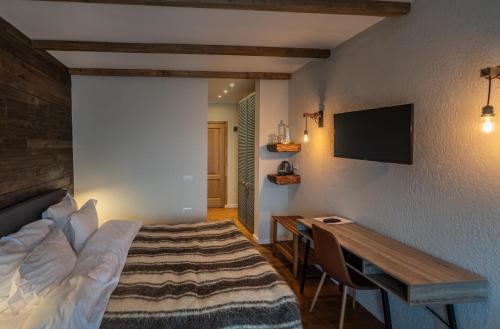 a bedroom with a bed and a desk and a television at Pensiunea Belvedere in Tîrgu Neamţ